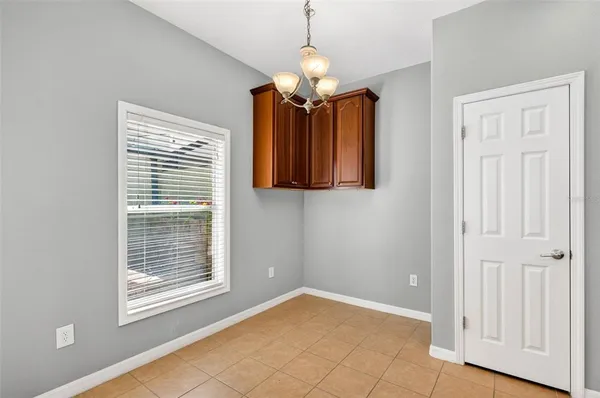 a view of an empty room with chandelier and wooden floor