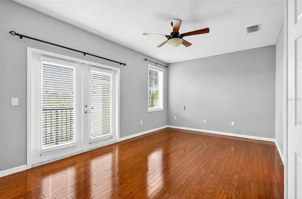 an empty room with wooden floor and windows