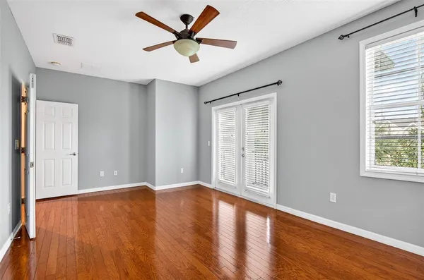 a view of empty room with wooden floor and fan