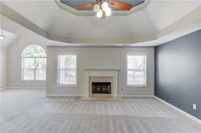 an empty room with chandelier fan and windows