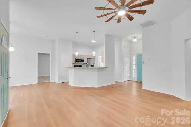 a view of an empty room with wooden floor and windows