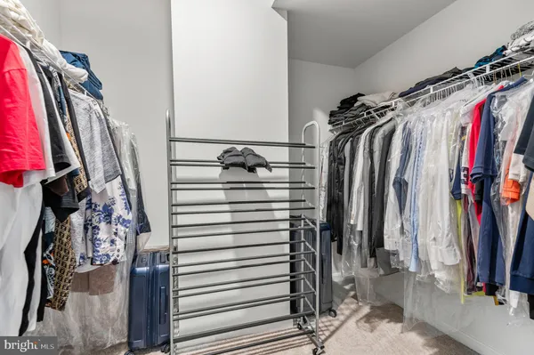 a view of walk in closet with clothes and shoes