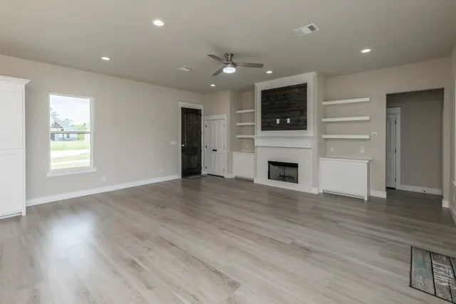 an empty room with wooden floor and fireplace