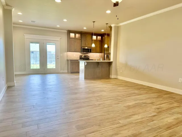a view of a kitchen and an empty room with wooden floor