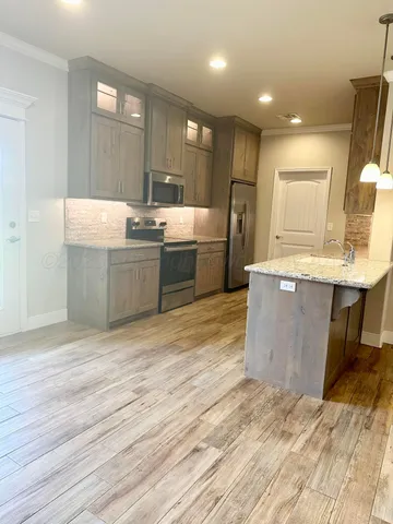a large kitchen with stainless steel appliances kitchen island granite countertop a sink and cabinets