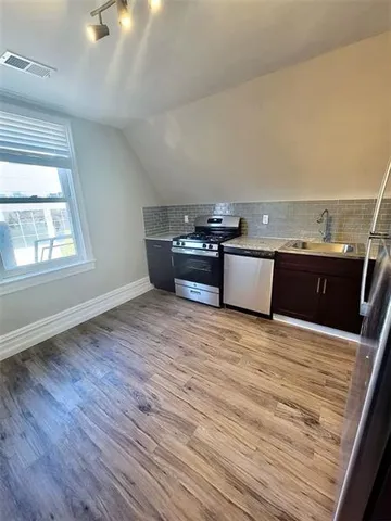 a view of a room with wooden floor and black appliances