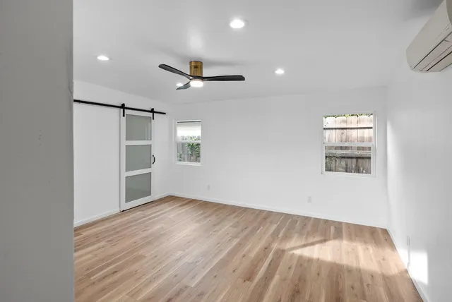 an empty room with wooden floor and windows