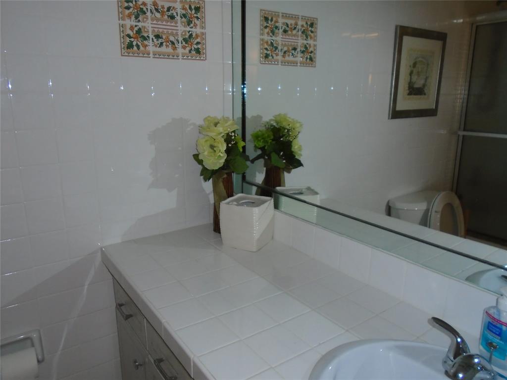 3165 Northeast 48th Court, Unit 110 Lighthouse Point, FL 33064 - Photo 22 of 49 a white vase with flowers and on a table