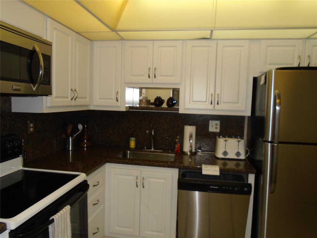 3165 Northeast 48th Court, Unit 110 Lighthouse Point, FL 33064 - Photo 29 of 49 a kitchen with stainless steel appliances granite countertop a refrigerator and a stove top oven