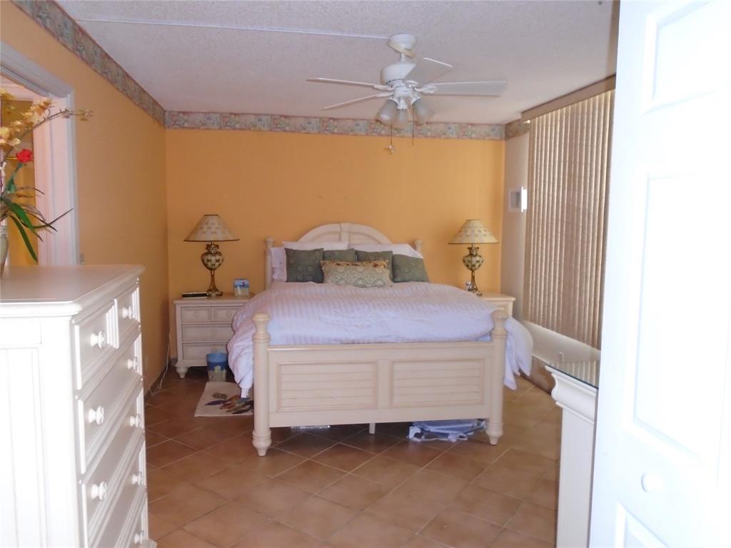3165 Northeast 48th Court, Unit 110 Lighthouse Point, FL 33064 - Photo 45 of 49 a bedroom with a bed and a chandelier
