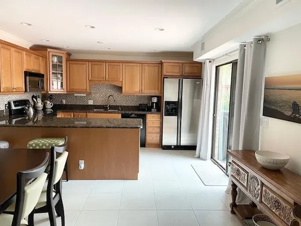 a kitchen with stainless steel appliances granite countertop a refrigerator a stove a sink dishwasher and white cabinets with wooden floor