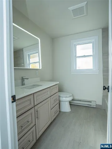 a bathroom with a granite countertop toilet a sink and mirror