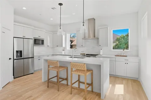 a kitchen with stainless steel appliances granite countertop a sink a stove a refrigerator and island with wooden floor