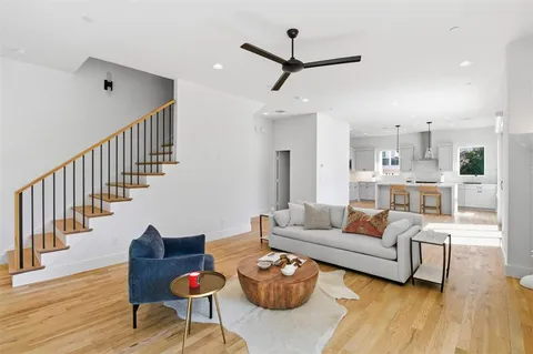 a living room with furniture kitchen view and a wooden floor
