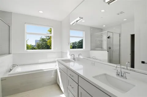 a bathroom with a double vanity sink large mirror and a bathtub