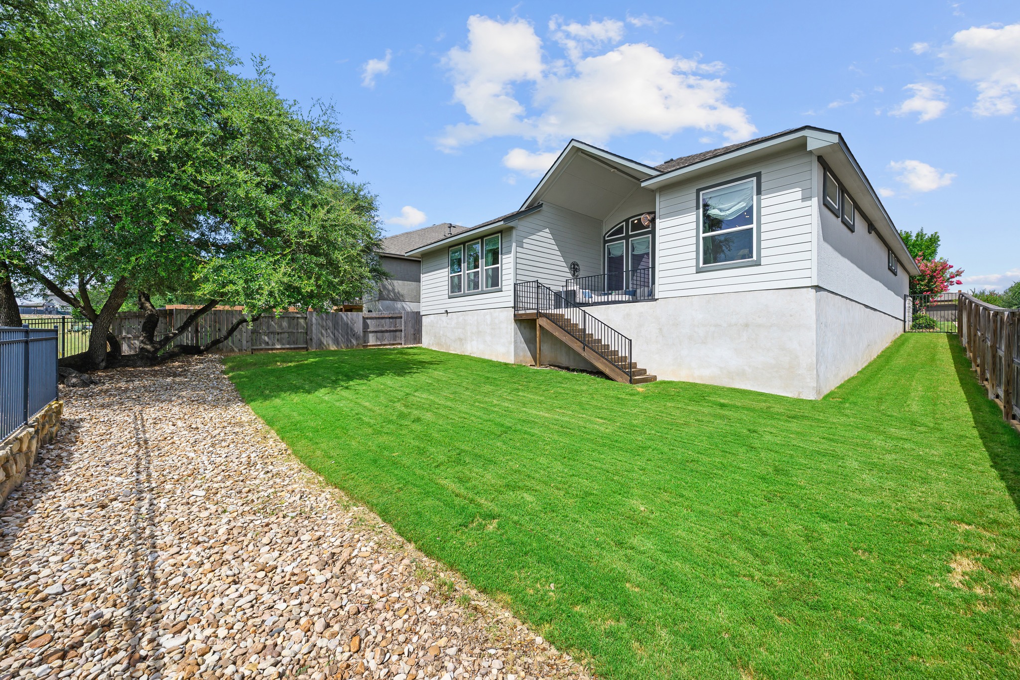 68 Rancho Trail Georgetown, TX 78628 - Photo 25 of 39 A tiered backyard offers lush green grass and a charming patio accessible via a set of exterior stairs.