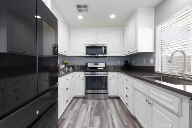 a kitchen with granite countertop white cabinets and stainless steel appliances