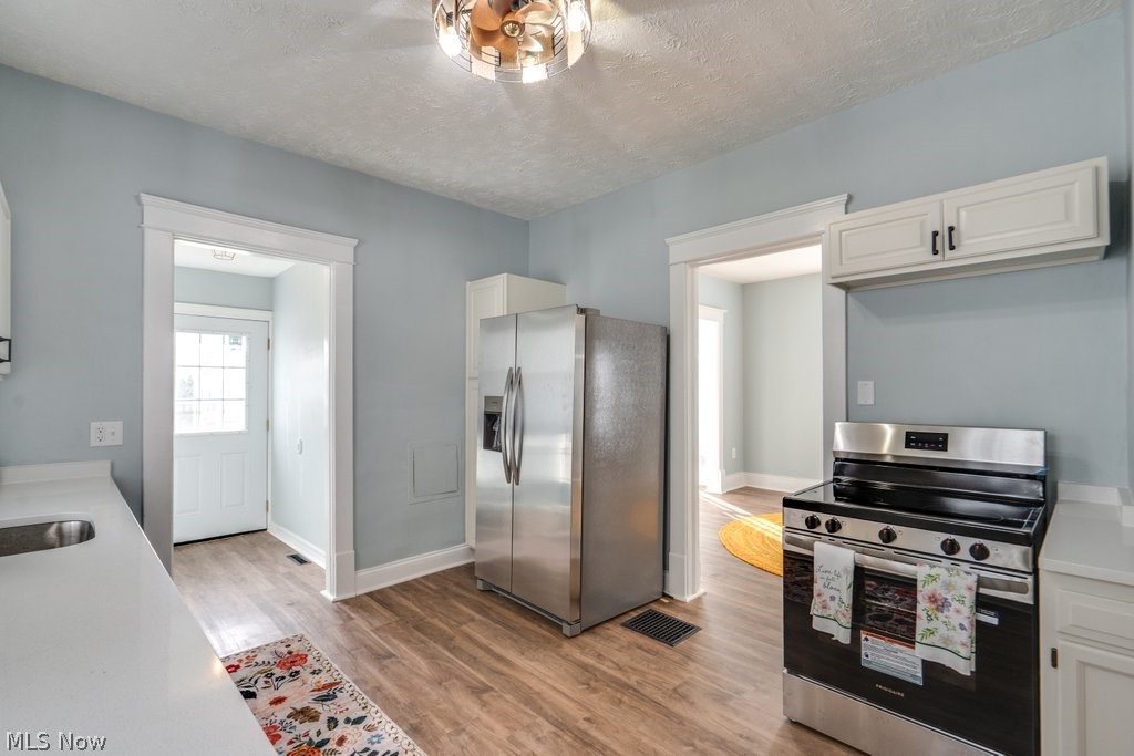 12 South 4th Street Rittman, OH 44270 - Photo 12 of 48 Kitchen with stainless steel appliances, a textured ceiling, white cabinetry, and light wood-style flooring