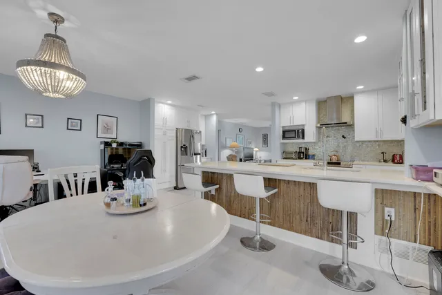a kitchen with stainless steel appliances a dining table chairs stove and cabinets