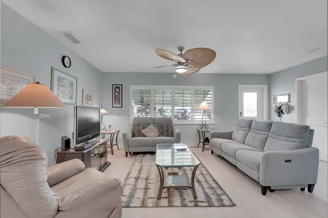 a living room with furniture ceiling fan and a large window