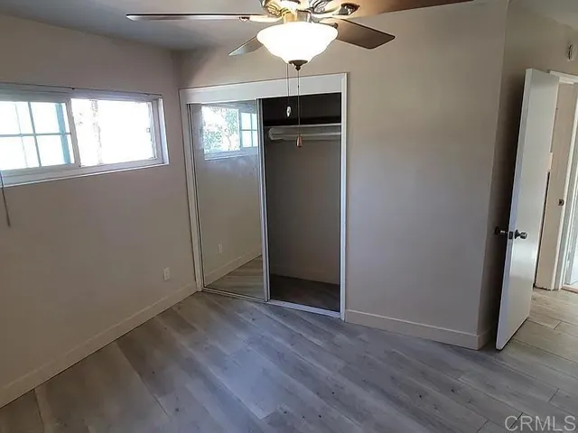 an empty room with wooden floor cabinet and windows