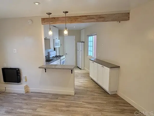 a view of a living room and kitchen with wooden floor