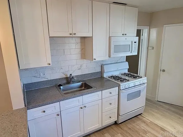 a kitchen with granite countertop white cabinets and white appliances