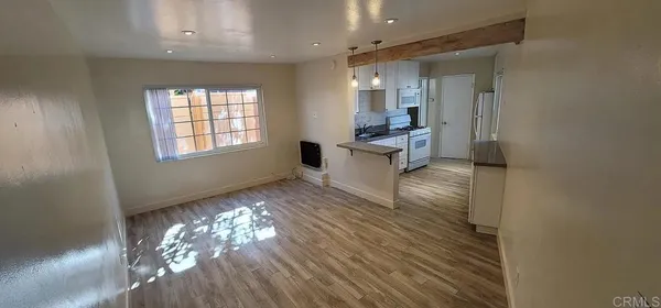 a large white kitchen with granite countertop a dishwasher a stove a dining table and chairs with wooden floor