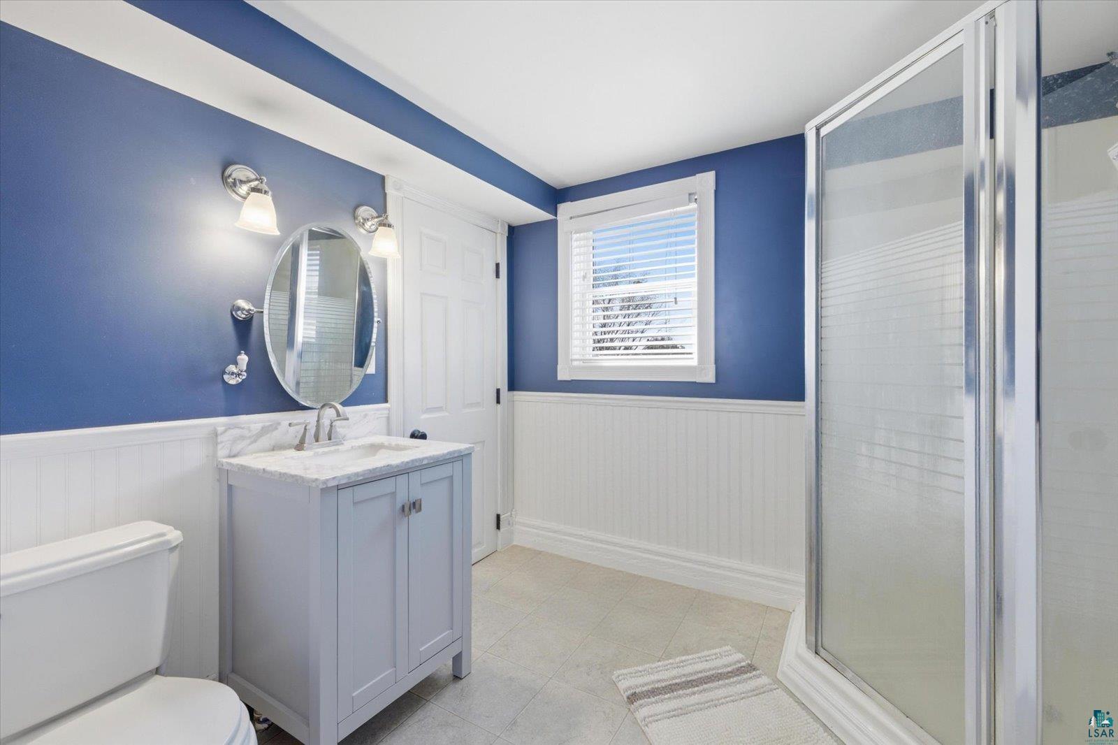 50 Main Street Soudan, MN 55782 - Photo 22 of 31 Bathroom featuring a single vanity with stone countertop, beadboard wainscoting, and a glass-enclosed shower
