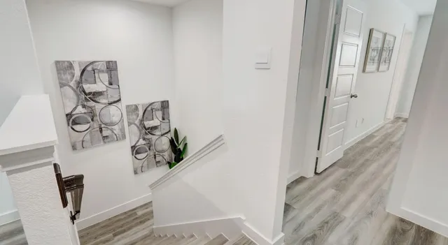 a view of a hallway with white walls and wooden floor
