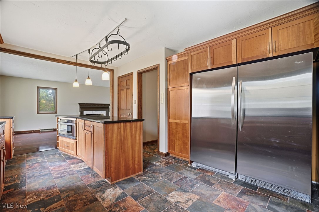 11710 Butternut Road Chardon, OH 44024 - Photo 6 of 48 Kitchen featuring stainless steel appliances, brown cabinetry, pendant lighting, dark stone finish floors, and a kitchen island