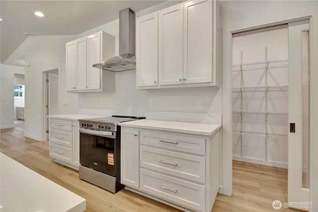 a kitchen with stainless steel appliances granite countertop a stove and a white cabinet