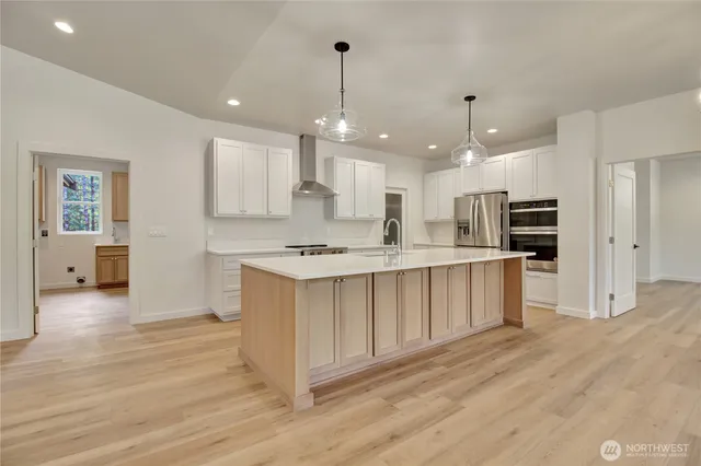a large kitchen with stainless steel appliances kitchen island a large counter top and wooden floors
