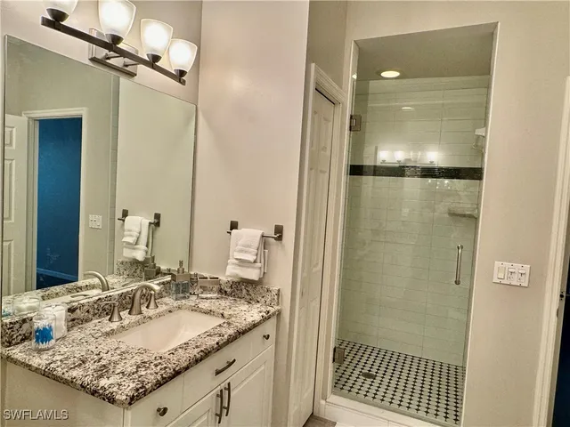 a bathroom with a granite countertop sink a mirror and shower