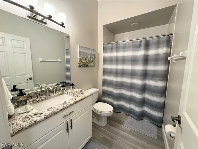 a bathroom with a granite countertop sink toilet a mirror and shower