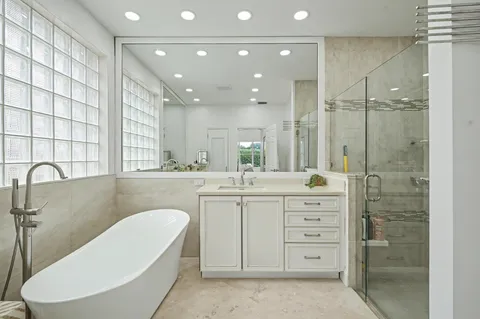 a bathroom with a double vanity sink a mirror a bathtub and shower