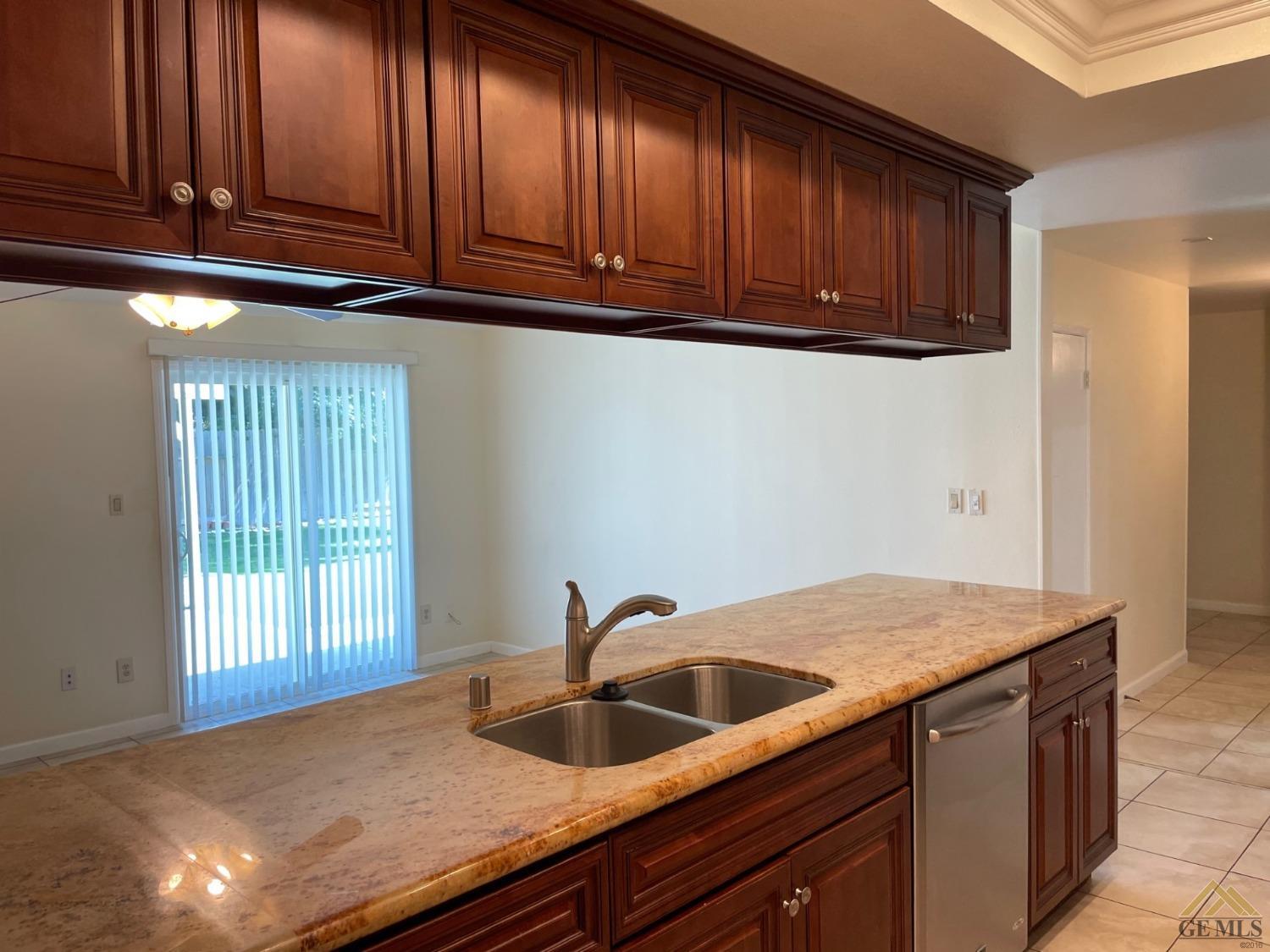 Undisclosed Address Bakersfield, CA 93311 - Photo 4 of 20 a kitchen with granite countertop wood cabinets a sink and dishwasher