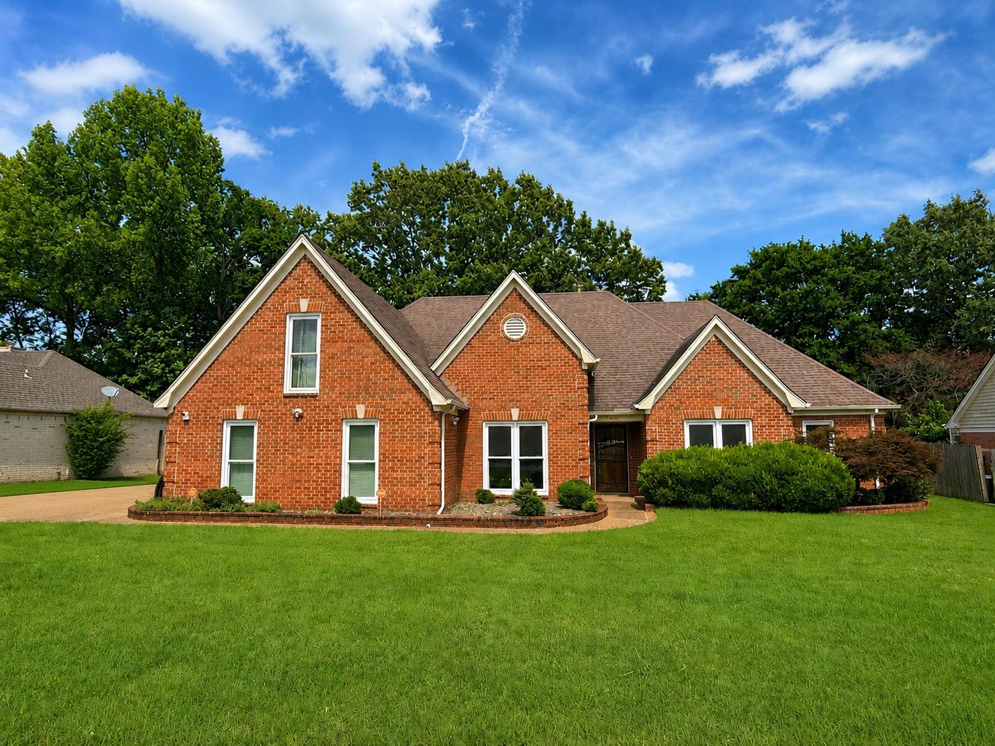 326 South Sanga Road Cordova, TN 38018 - Photo 1 of 32 Brick facade residence featuring a front gable, gabled roofline, mature landscaping, and an attached garage with a paved driveway