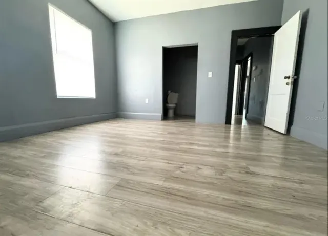 an empty room with wooden floor and windows