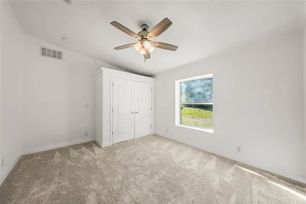 a view of an empty room with chandelier fan and fire place