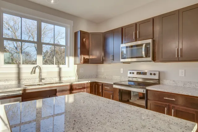 a kitchen with stainless steel appliances wooden cabinets a stove a sink and a microwave