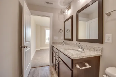 a bathroom with a granite countertop sink a toilet and a mirror
