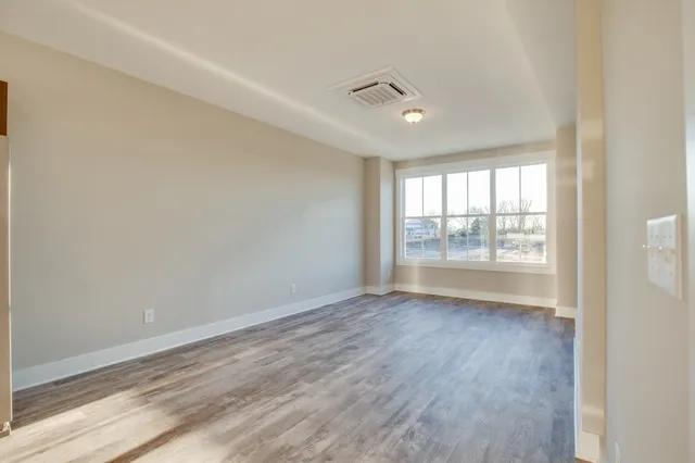 an empty room with wooden floor and windows