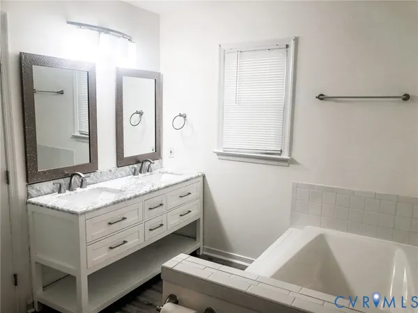 a bathroom with a tub sink and mirror