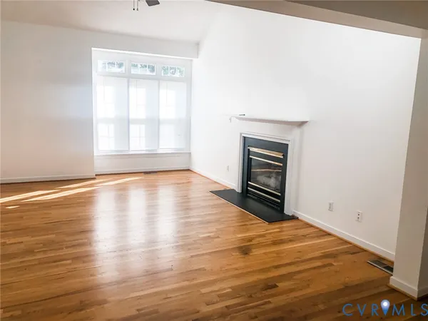 an empty room with wooden floor cabinet and windows