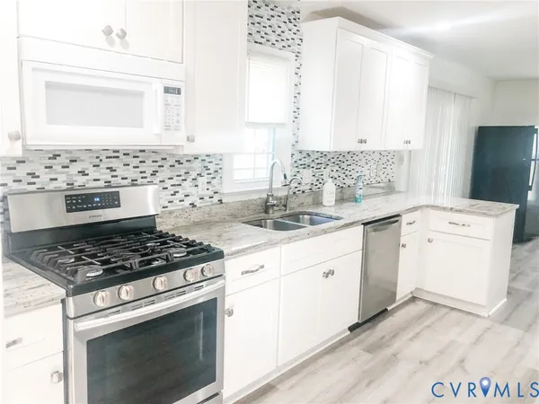a kitchen with granite countertop white cabinets and white appliances