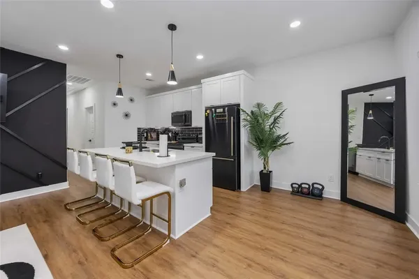 a large white kitchen with a sink and stainless steel appliances