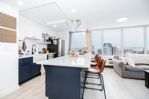 a living room with kitchen island furniture a large window and a sink