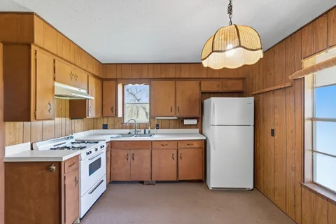a kitchen that has a lot of cabinets stainless steel appliances and a large window