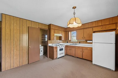 a kitchen with stainless steel appliances granite countertop a refrigerator a oven and white cabinets